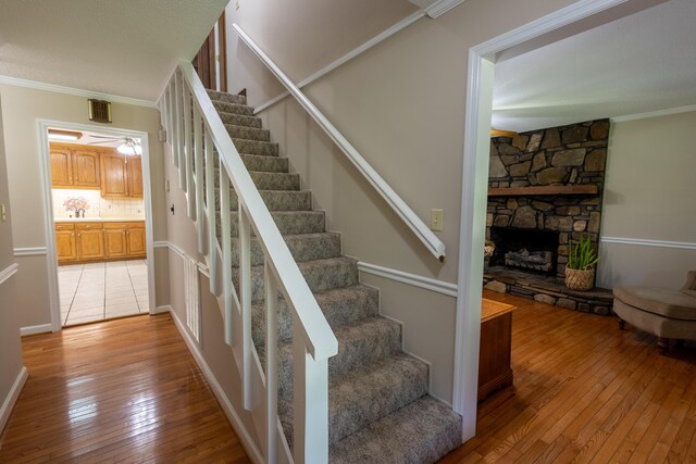 446 Jamestown Rd, Menlo, GA 30731 - staircase with ornamental molding, a stone fireplace, sink, and hardwood / wood-style floors