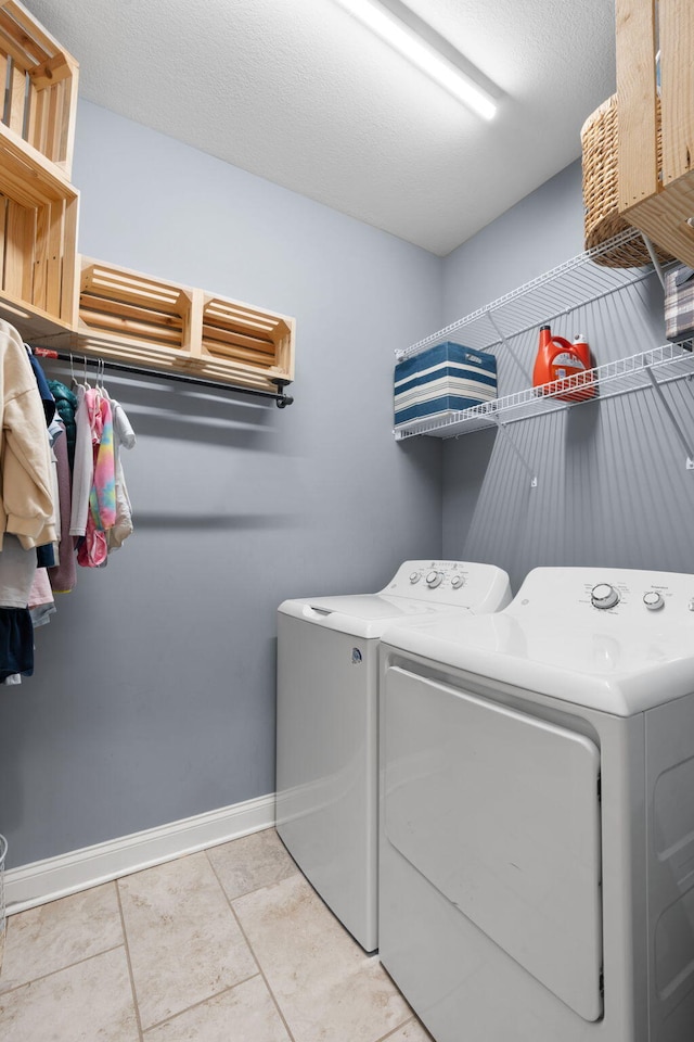 laundry area with light tile patterned floors, a textured ceiling, laundry area, independent washer and dryer, and baseboards