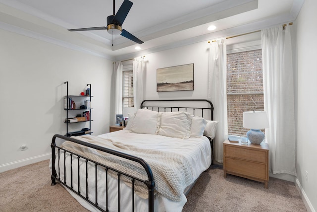 carpeted bedroom with crown molding, ceiling fan, and a tray ceiling