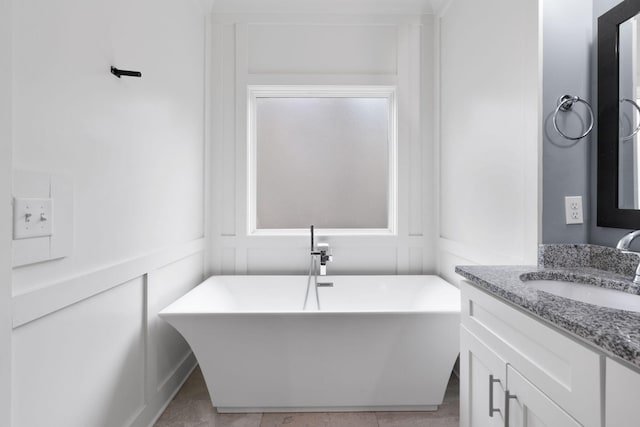 bathroom featuring a soaking tub, a decorative wall, and vanity