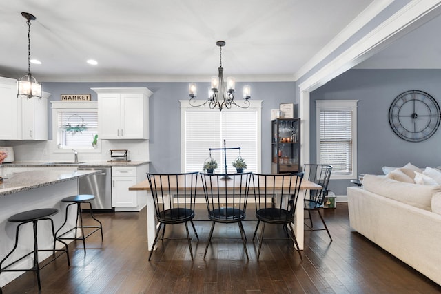 dining space with crown molding, dark wood-type flooring, sink, and a chandelier