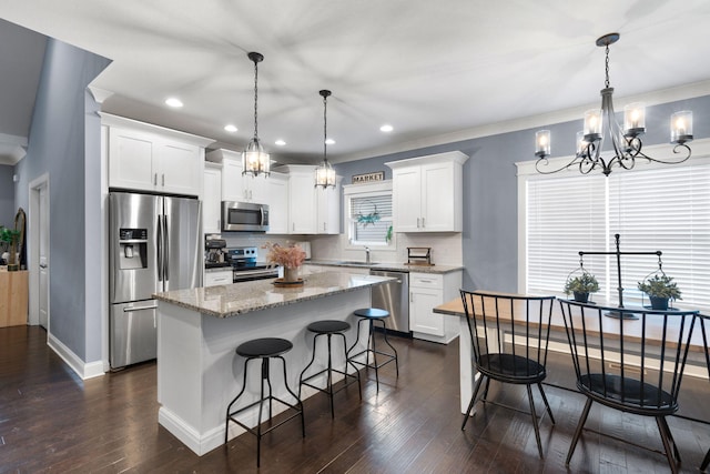 kitchen featuring a kitchen island, appliances with stainless steel finishes, white cabinetry, pendant lighting, and a sink