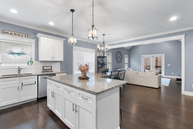 kitchen with sink, decorative light fixtures, dishwasher, light stone countertops, and white cabinets