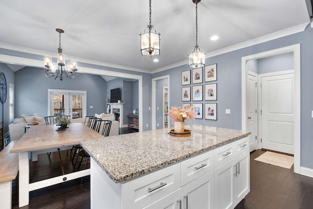 kitchen with dark wood-type flooring, decorative light fixtures, light stone countertops, and white cabinets