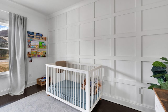 bedroom featuring a nursery area and dark wood-type flooring