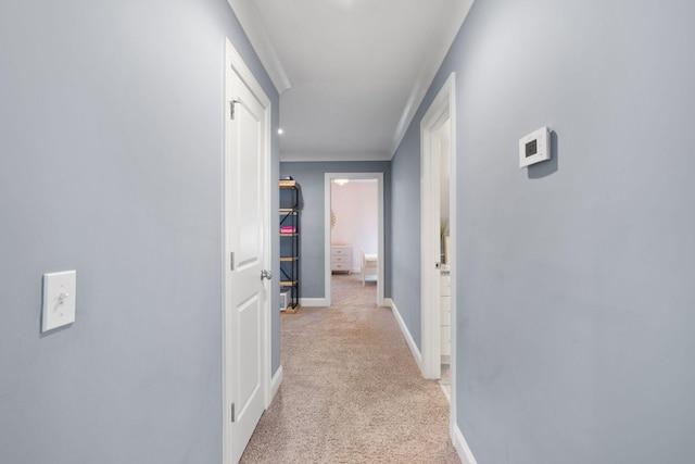 hallway featuring light colored carpet and baseboards