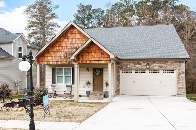 craftsman inspired home featuring a garage, stone siding, driveway, and a shingled roof