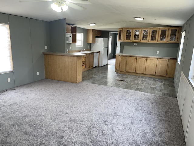 kitchen featuring white appliances, vaulted ceiling, light carpet, kitchen peninsula, and ceiling fan