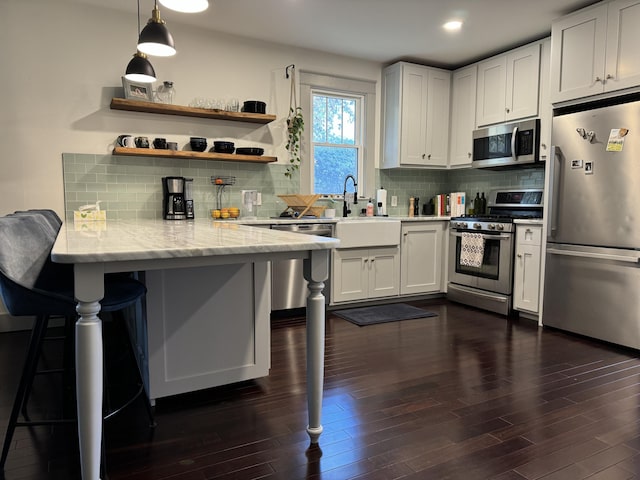 kitchen with a breakfast bar, white cabinetry, stainless steel appliances, decorative light fixtures, and kitchen peninsula