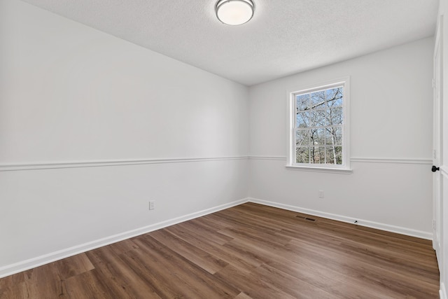 spare room featuring wood-type flooring and a textured ceiling