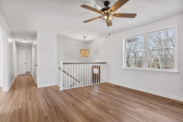 spare room with a healthy amount of sunlight, a textured ceiling, ceiling fan, and light hardwood / wood-style flooring