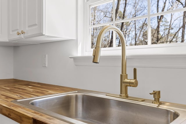 interior details featuring white cabinetry, butcher block countertops, and sink