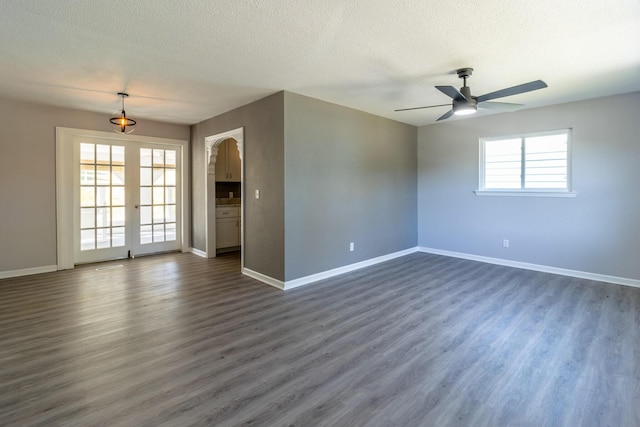 spare room with ceiling fan, a textured ceiling, dark hardwood / wood-style flooring, and french doors