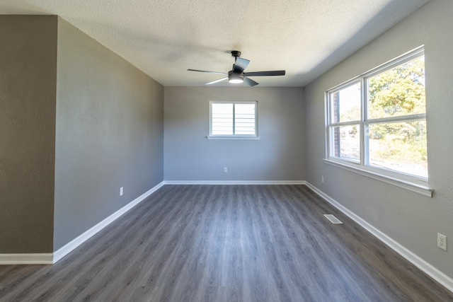 unfurnished room featuring dark hardwood / wood-style flooring, ceiling fan, a wealth of natural light, and a textured ceiling