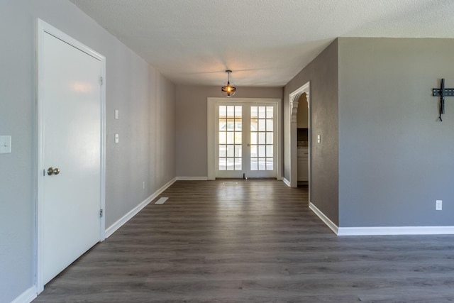 unfurnished room featuring dark wood-type flooring, french doors, and a textured ceiling