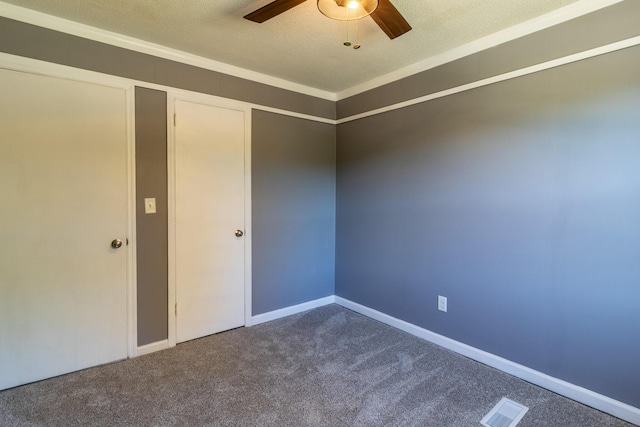 carpeted empty room featuring a textured ceiling, ornamental molding, and ceiling fan