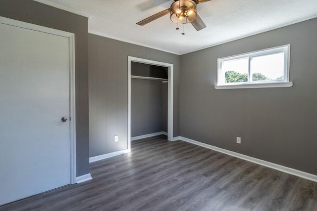 unfurnished bedroom featuring dark wood-type flooring, a textured ceiling, ornamental molding, a closet, and ceiling fan