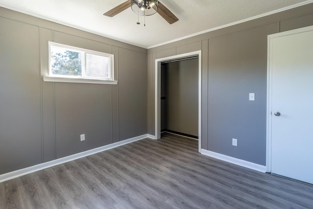 unfurnished bedroom featuring ceiling fan, wood-type flooring, ornamental molding, a textured ceiling, and a closet