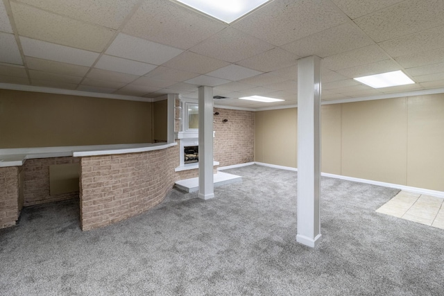 basement featuring ornamental molding, brick wall, carpet floors, and a drop ceiling