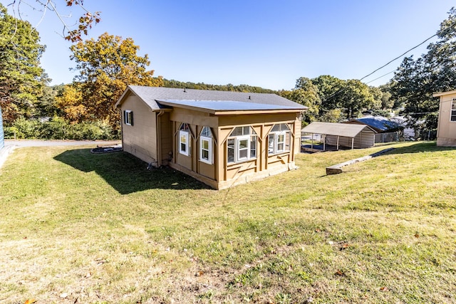 back of house featuring a carport and a lawn