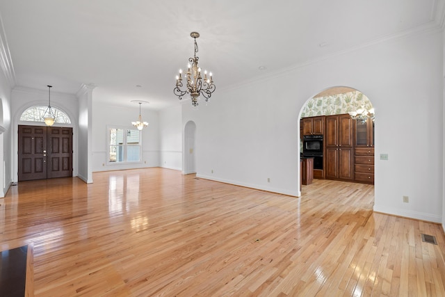 unfurnished living room featuring light wood-style floors, arched walkways, visible vents, and a notable chandelier