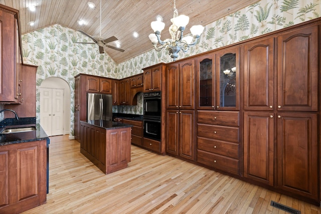 kitchen with wallpapered walls, a center island, a sink, and freestanding refrigerator