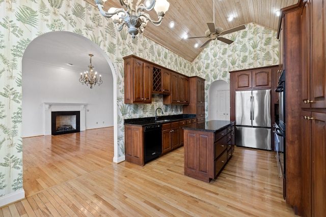 kitchen featuring arched walkways, a center island, freestanding refrigerator, dishwasher, and wallpapered walls