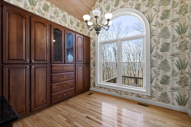 unfurnished dining area with light wood-style floors, visible vents, and wallpapered walls