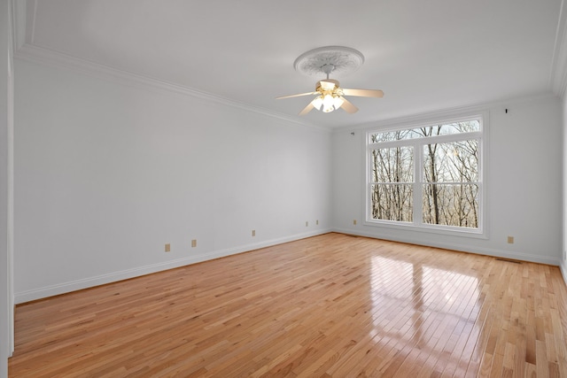 empty room with baseboards, light wood finished floors, a ceiling fan, and crown molding