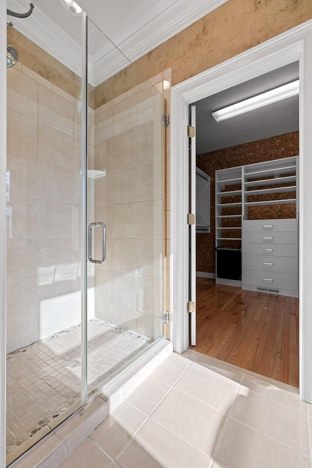 bathroom with a stall shower, ornamental molding, and tile patterned floors