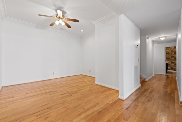 empty room featuring visible vents, a fireplace, crown molding, and light wood-style flooring