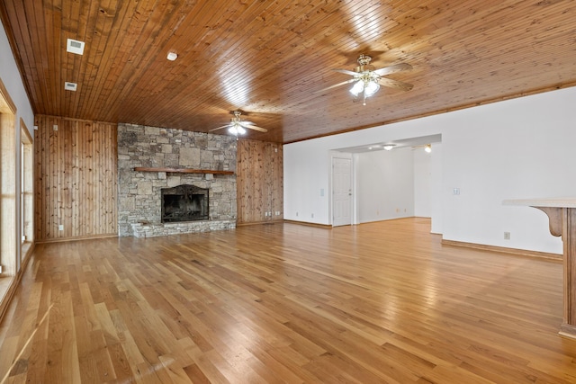 unfurnished living room featuring ceiling fan, a stone fireplace, wood ceiling, and light wood-style flooring