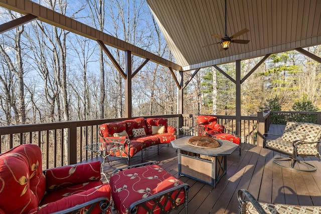 deck featuring a ceiling fan and an outdoor living space with a fire pit