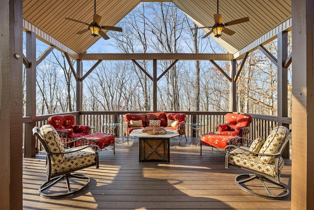 deck featuring a ceiling fan and an outdoor living space with a fire pit