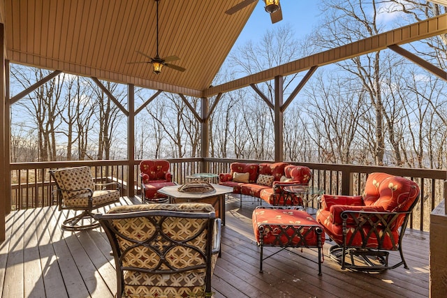 wooden deck with a ceiling fan and an outdoor living space with a fire pit