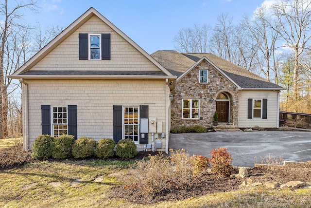 view of front of house featuring stone siding, a patio, and driveway