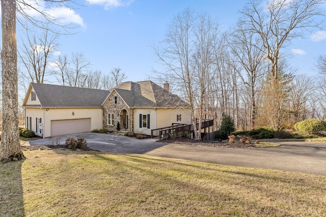 french country inspired facade featuring stone siding, a chimney, aphalt driveway, an attached garage, and a front lawn