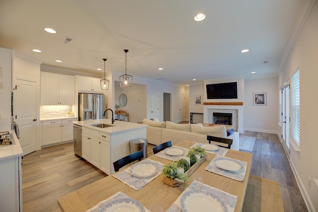 dining space with crown molding, sink, and light wood-type flooring