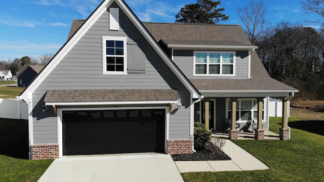 view of front of house featuring a garage, a front yard, and covered porch