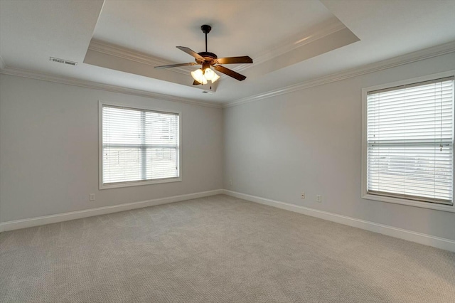 carpeted spare room with crown molding, ceiling fan, and a raised ceiling