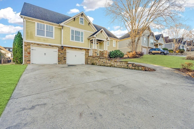 view of front of property featuring roof with shingles, an attached garage, a front yard, stone siding, and driveway