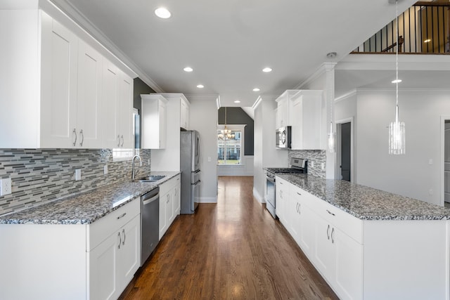 kitchen with decorative light fixtures, sink, stainless steel appliances, and white cabinetry