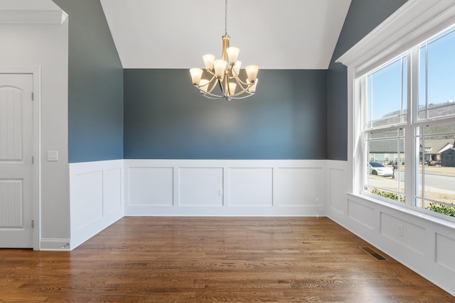 spare room with vaulted ceiling, hardwood / wood-style floors, and a chandelier