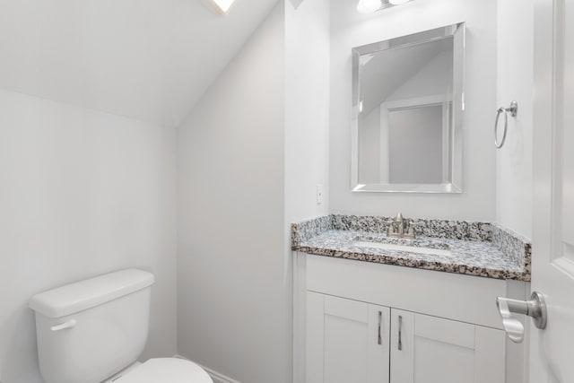 bathroom with vanity, vaulted ceiling, and toilet