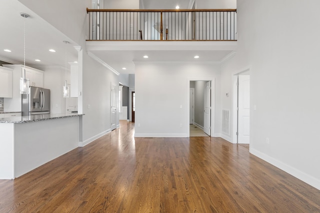 unfurnished living room with ornamental molding, dark hardwood / wood-style floors, and a towering ceiling