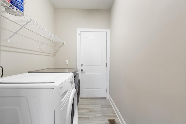 clothes washing area featuring washing machine and dryer and light wood-type flooring