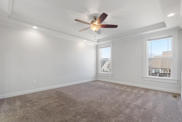 spare room with a tray ceiling, carpet floors, crown molding, and ceiling fan