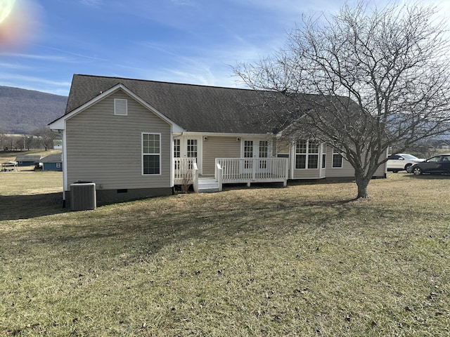 view of front of home with a wooden deck, central AC unit, and a front lawn