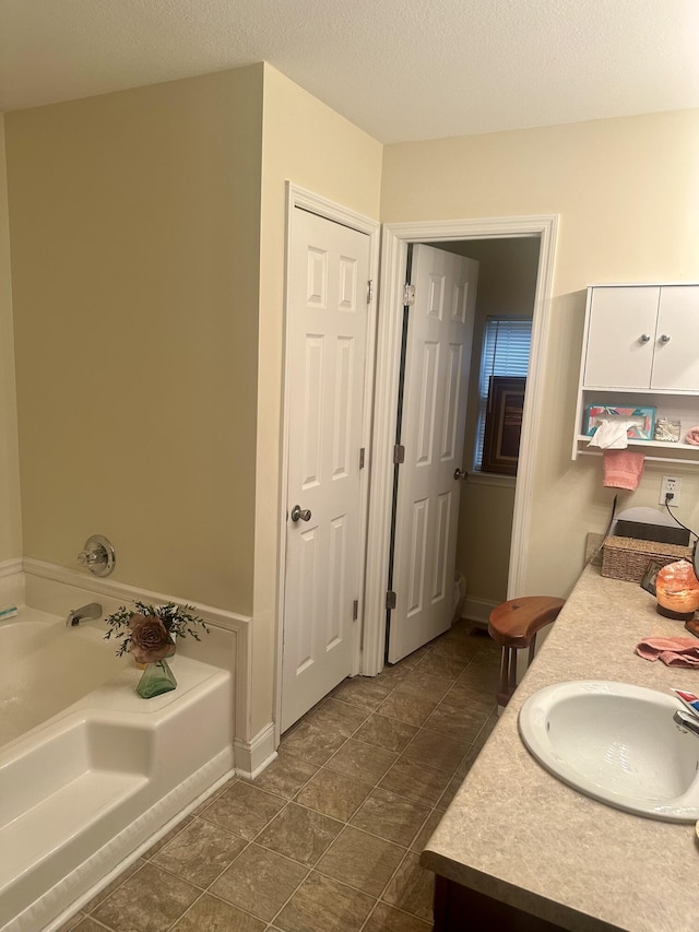 bathroom featuring vanity, a textured ceiling, and a bathing tub