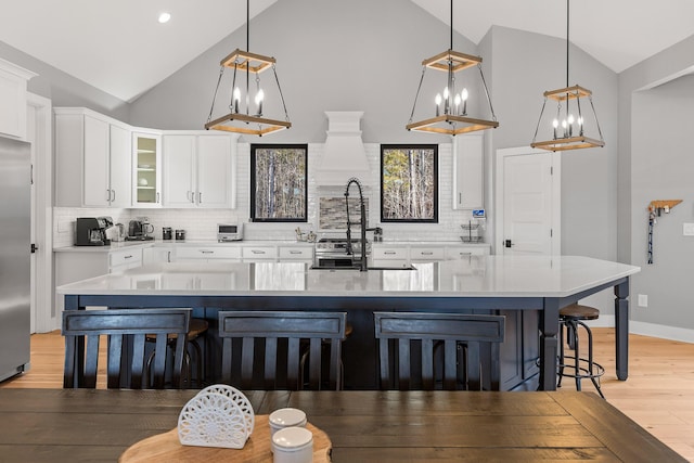 kitchen with sink, pendant lighting, white cabinets, and a spacious island